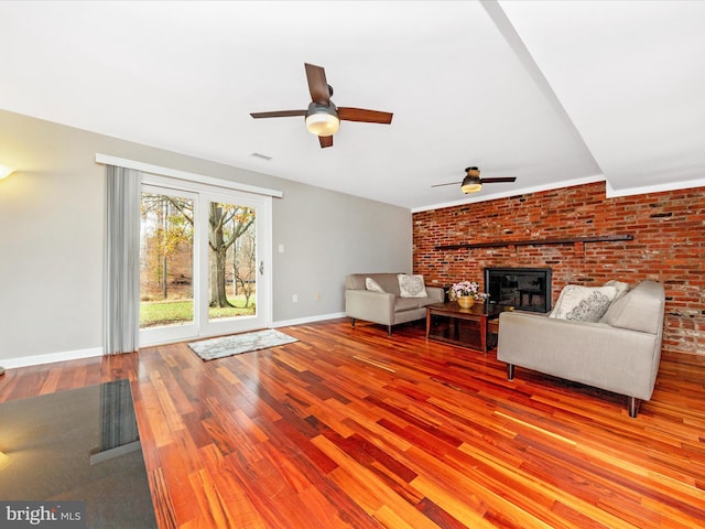 unfurnished living room with hardwood / wood-style flooring, ceiling fan, a fireplace, and brick wall