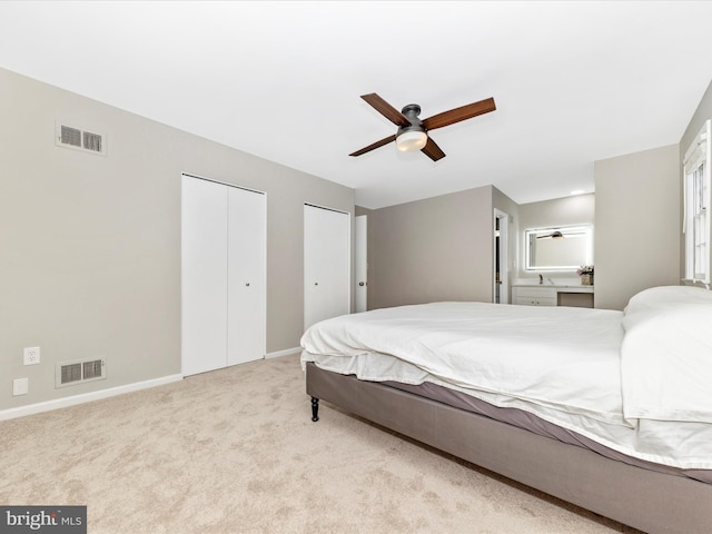 bedroom featuring two closets, light colored carpet, and ceiling fan