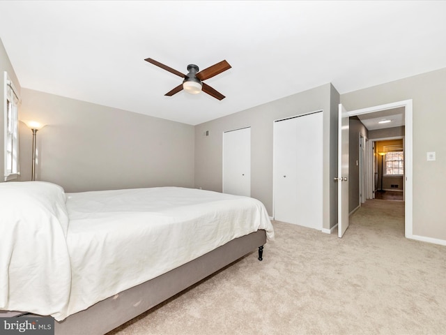 carpeted bedroom featuring multiple closets and ceiling fan