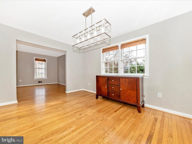 spare room featuring light hardwood / wood-style floors and an inviting chandelier