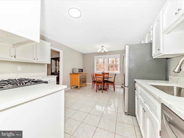 kitchen featuring an inviting chandelier, white cabinets, sink, light tile patterned floors, and appliances with stainless steel finishes