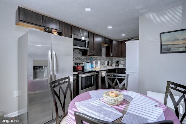 kitchen with backsplash, sink, dark brown cabinetry, appliances with stainless steel finishes, and a textured ceiling