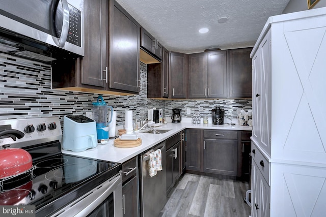 kitchen featuring dark brown cabinets, stainless steel appliances, a textured ceiling, light hardwood / wood-style floors, and tasteful backsplash