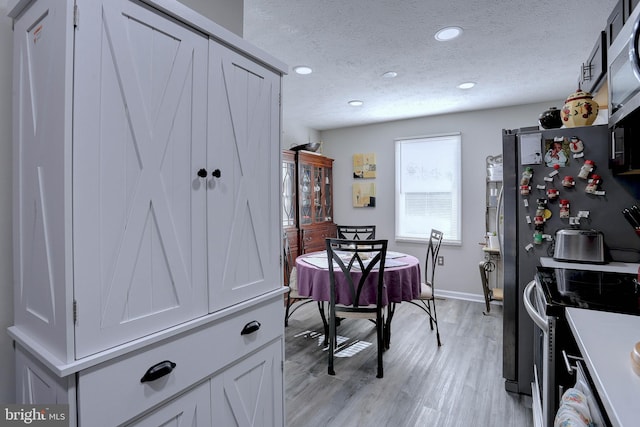 dining room featuring a textured ceiling and light wood-type flooring