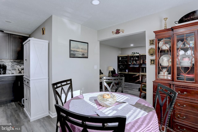 dining space featuring light hardwood / wood-style flooring and a textured ceiling