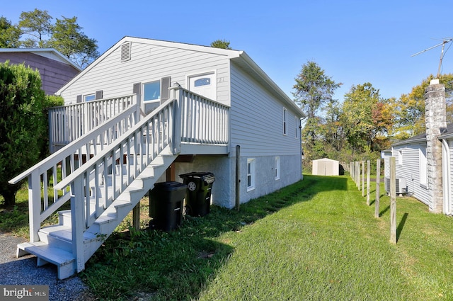 back of property with a wooden deck, central AC, and a lawn