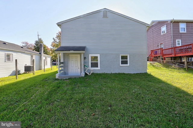 rear view of property with a wooden deck, cooling unit, and a lawn