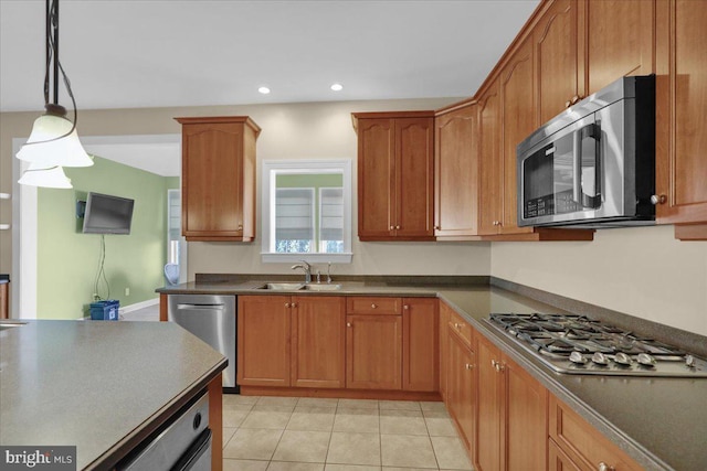 kitchen with sink, appliances with stainless steel finishes, pendant lighting, and light tile patterned floors