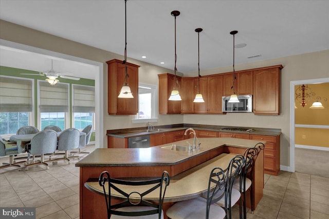 kitchen featuring light tile patterned floors, appliances with stainless steel finishes, sink, and a center island with sink