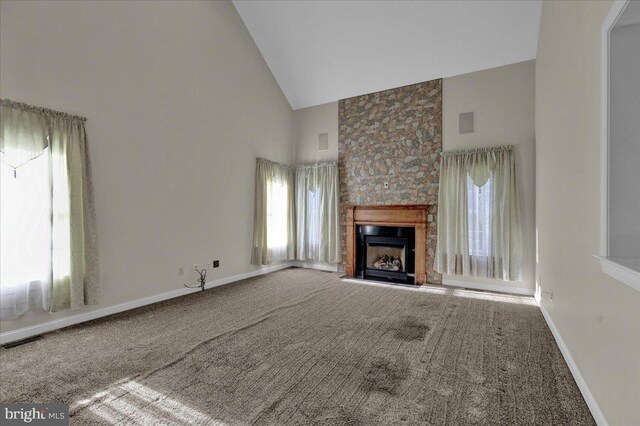 unfurnished living room with a wealth of natural light, carpet, a large fireplace, and high vaulted ceiling