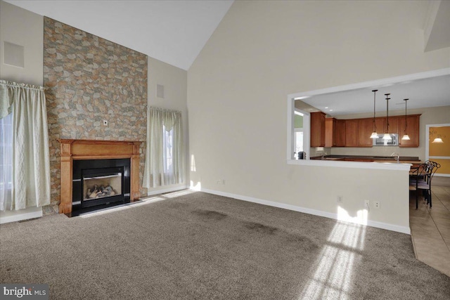 unfurnished living room with an inviting chandelier, carpet floors, and high vaulted ceiling