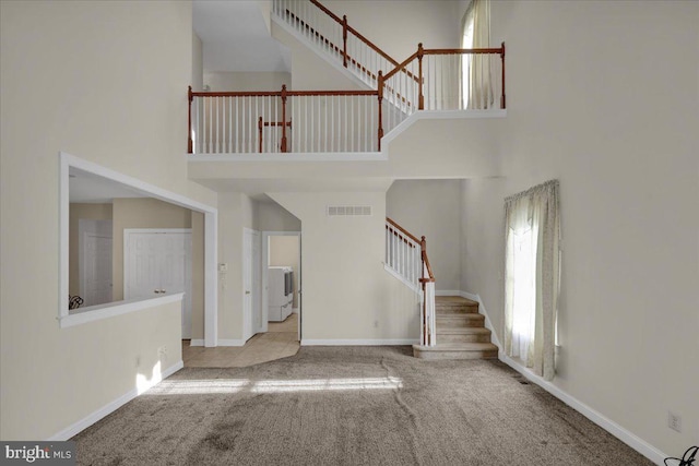 entrance foyer featuring a high ceiling, light carpet, and washer / clothes dryer