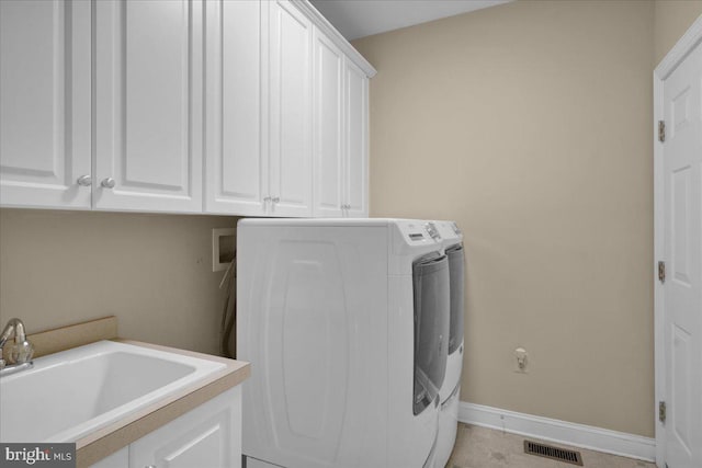 clothes washing area with sink, independent washer and dryer, and cabinets