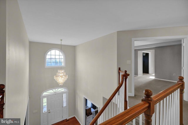 carpeted foyer entrance featuring a notable chandelier