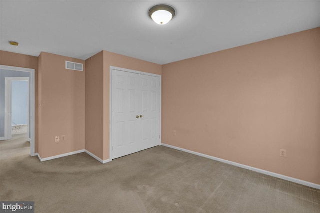 unfurnished bedroom with a closet and light colored carpet