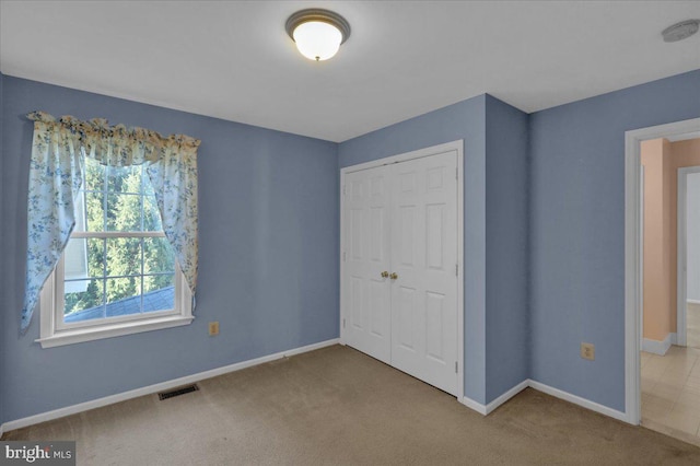 unfurnished bedroom with a closet and light carpet