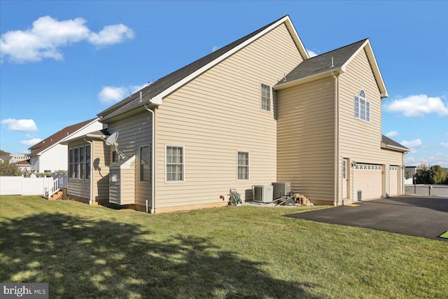 back of house with a yard, a garage, and central AC unit