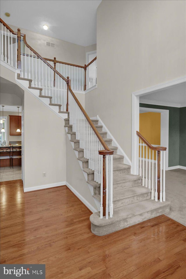 stairs featuring hardwood / wood-style flooring and a high ceiling