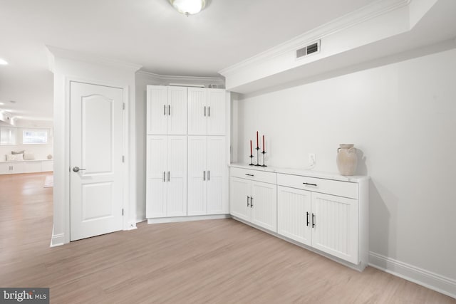 bar featuring ornamental molding, light hardwood / wood-style flooring, and white cabinets