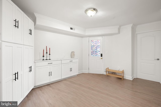 interior space with light hardwood / wood-style floors, white cabinets, and ornamental molding