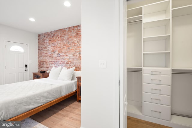 bedroom featuring a closet, brick wall, and light wood-type flooring