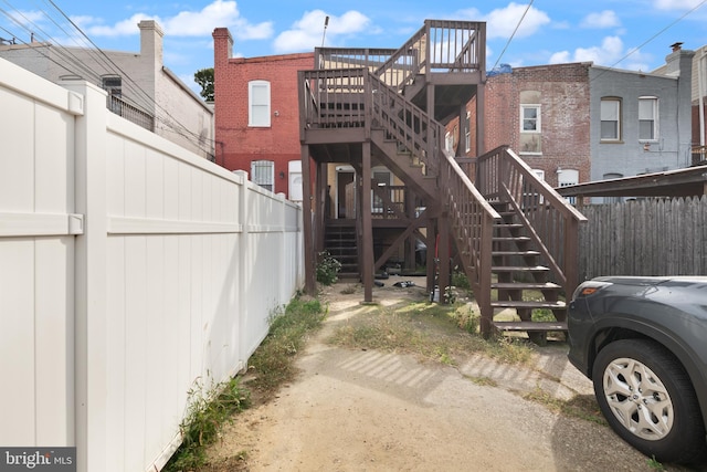 rear view of house featuring stairway and fence