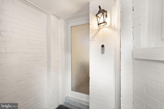 bathroom featuring brick wall and walk in shower