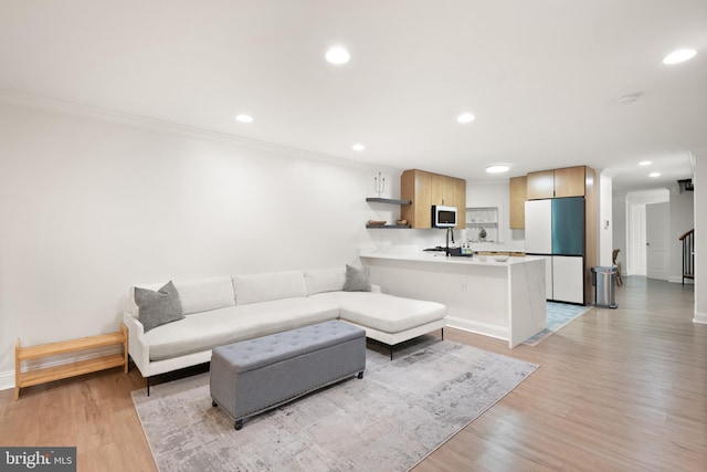 living room featuring baseboards, recessed lighting, ornamental molding, and light wood-type flooring