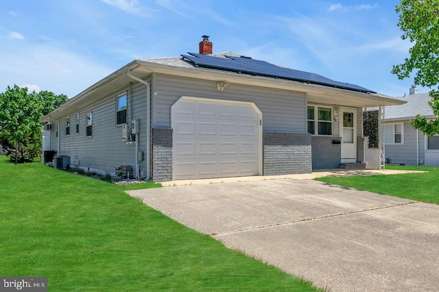 ranch-style home with solar panels, a front lawn, and a garage