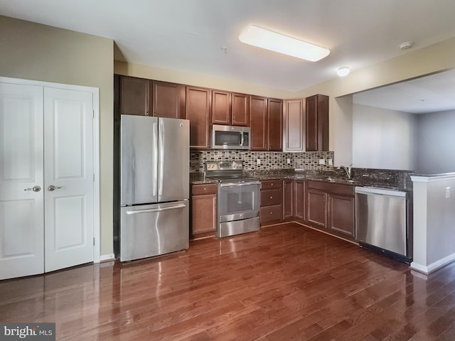 kitchen with sink, appliances with stainless steel finishes, dark hardwood / wood-style floors, and tasteful backsplash