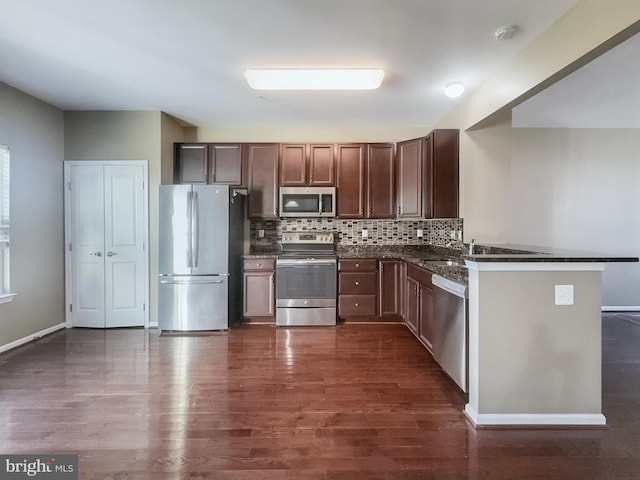 kitchen featuring decorative backsplash, kitchen peninsula, dark hardwood / wood-style floors, and stainless steel appliances