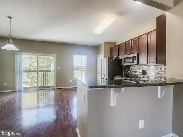 kitchen featuring a kitchen breakfast bar, kitchen peninsula, stainless steel appliances, and dark hardwood / wood-style flooring