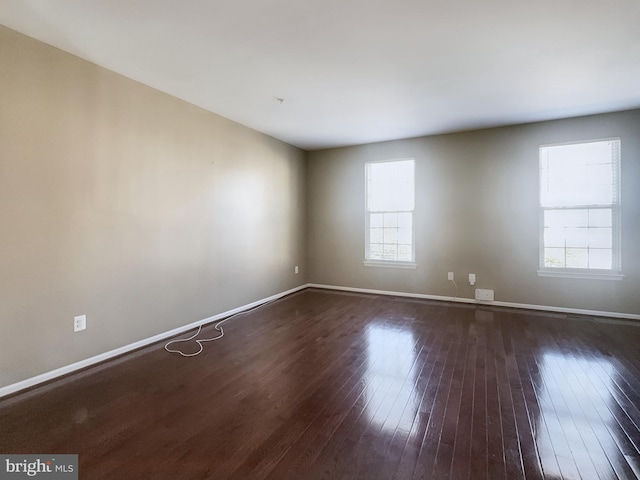 spare room featuring dark hardwood / wood-style flooring and plenty of natural light