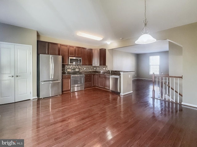 kitchen with sink, appliances with stainless steel finishes, pendant lighting, and dark hardwood / wood-style flooring