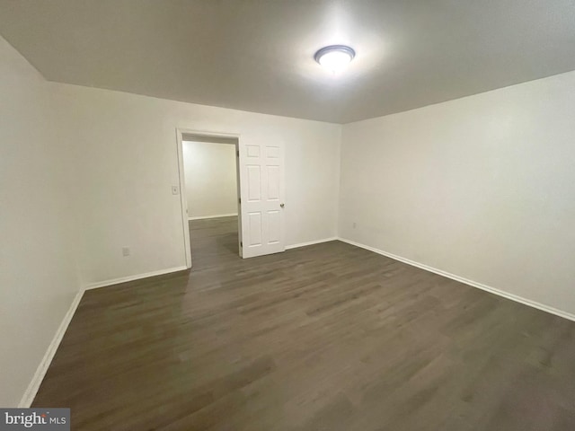 empty room featuring baseboards and dark wood-style flooring