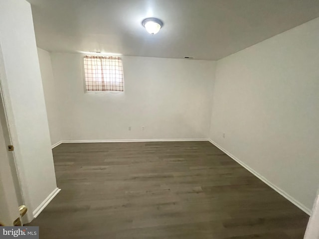 basement featuring baseboards and dark wood-type flooring