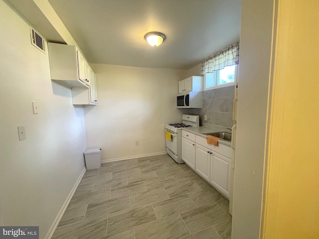 kitchen featuring white cabinets, light countertops, visible vents, white appliances, and baseboards