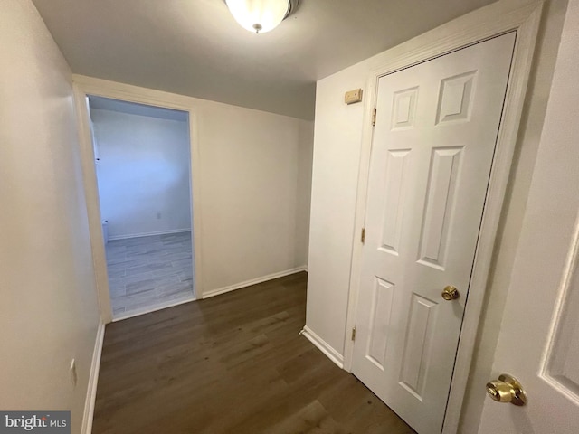 hallway with dark wood finished floors and baseboards