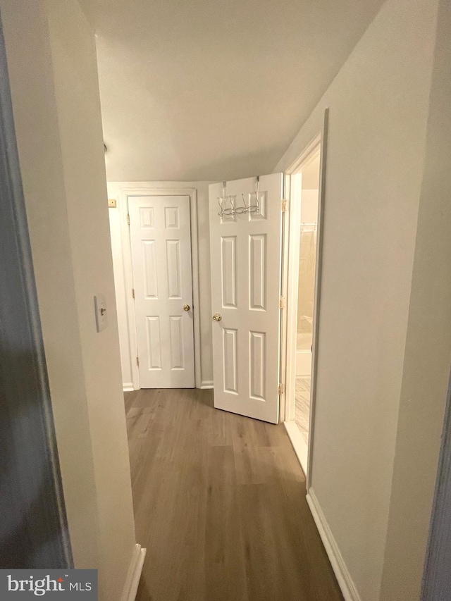 hall featuring baseboards, wood finished floors, and a chandelier