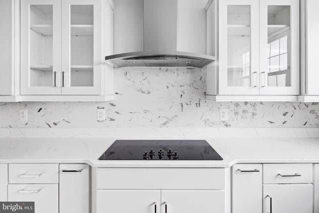 kitchen with black electric stovetop, light stone countertops, white cabinetry, wall chimney exhaust hood, and decorative backsplash