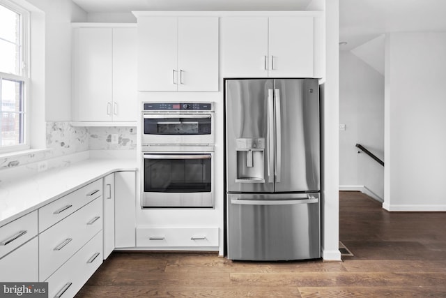 0 Triggerfish Dr, National Harbor, MD 20745 - kitchen featuring white cabinets, light stone counters, stainless steel appliances, wood finished floors, and decorative backsplash