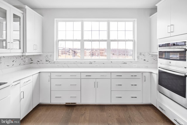0 Triggerfish Dr, National Harbor, MD 20745 - kitchen with dark wood finished floors, white cabinetry, stainless steel double oven, glass insert cabinets, and light countertops