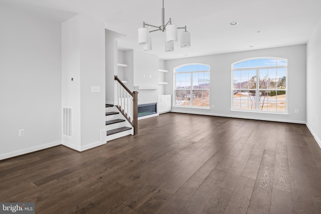 unfurnished living room featuring an inviting chandelier and dark hardwood / wood-style flooring