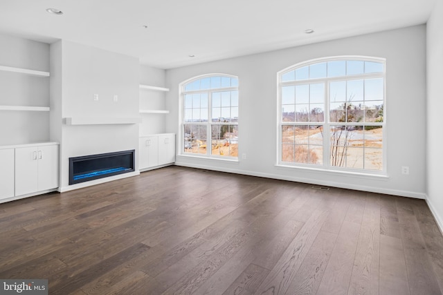 unfurnished living room with built in shelves and dark hardwood / wood-style flooring