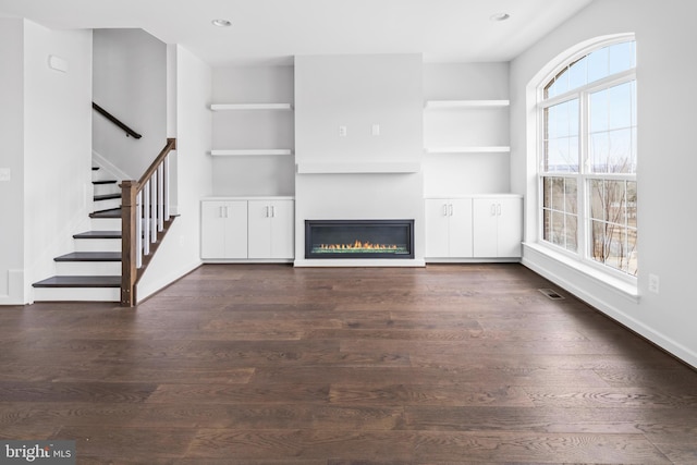 unfurnished living room featuring built in features and dark hardwood / wood-style flooring