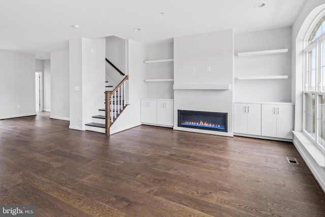 0 Triggerfish Dr, National Harbor, MD 20745 - unfurnished living room featuring a glass covered fireplace, recessed lighting, stairs, and dark wood finished floors