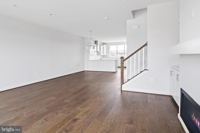 unfurnished living room with sink, dark hardwood / wood-style floors, and an inviting chandelier