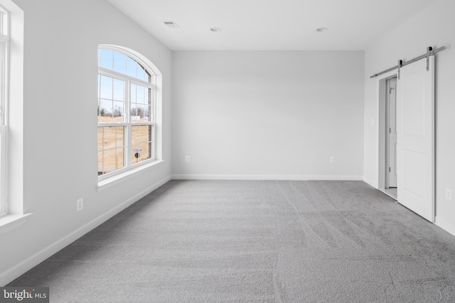 unfurnished bedroom with a barn door and light carpet