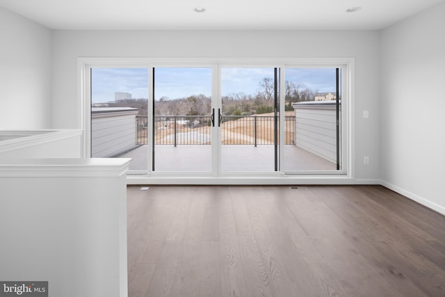 empty room with a wealth of natural light and hardwood / wood-style floors