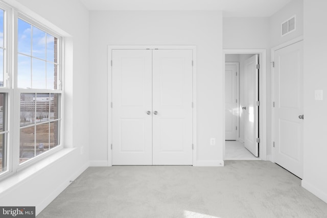 unfurnished bedroom featuring a closet, light carpet, and multiple windows